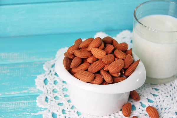 Leche de almendras en vaso con almendras en tazón, sobre fondo de madera de color —  Fotos de Stock