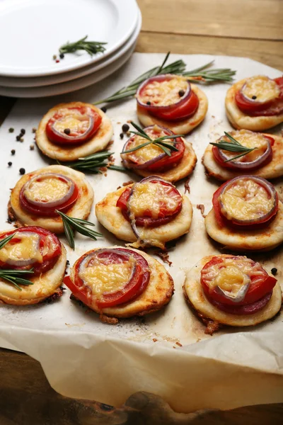 Pequeñas pizzas sobre papel de hornear de cerca — Foto de Stock