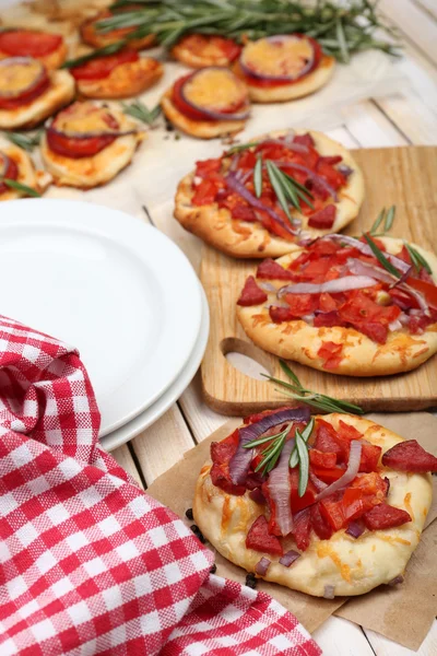 Small pizzas on baking paper close up — Stock Photo, Image