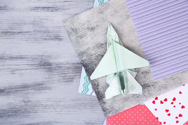 Origami avião e papéis de cor na mesa de madeira — Fotografia de Stock