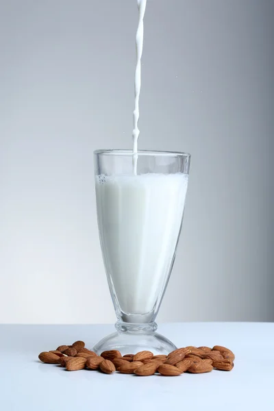 Le lait d'amande est versé dans du verre, sur fond gris — Photo