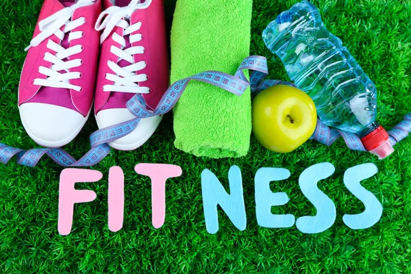 Fitness and healthy life. Conceptual photo. Gumshoes, towel, dumbbells and water bottle on green grass background — Stock Photo, Image