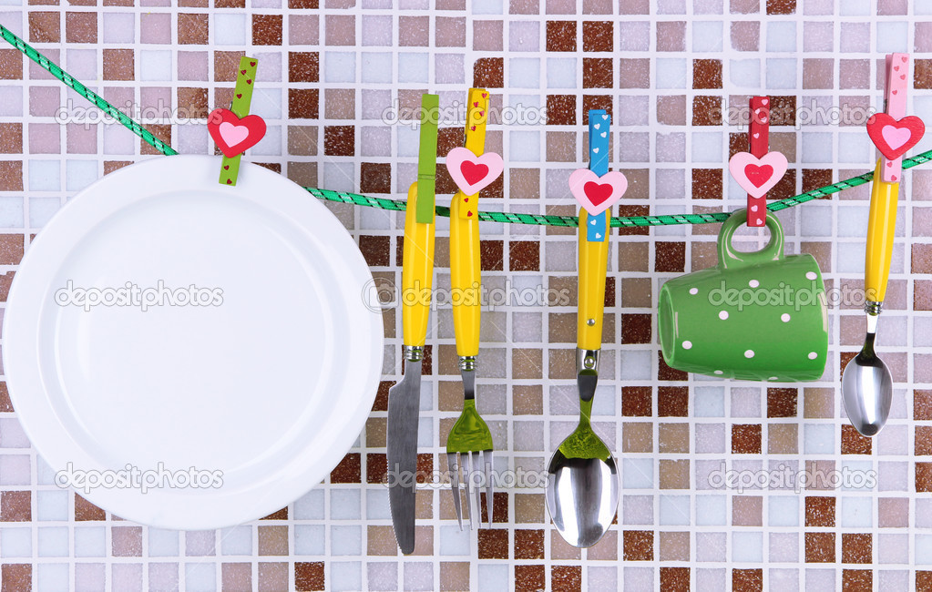 Tableware dried on rope on tile mosaic background