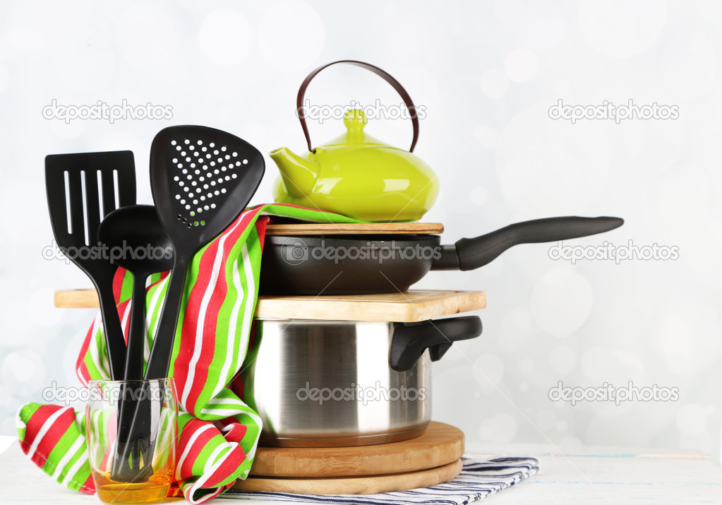 Stacked cooking equipment on wooden table, on light background