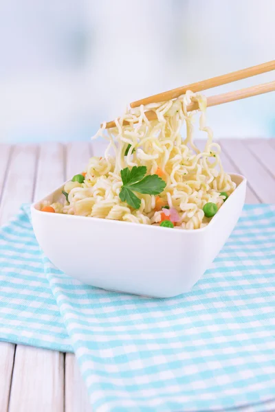 Tasty instant noodles with vegetables in bowl on table on light background — Stock Photo, Image