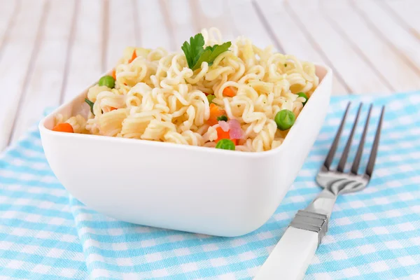 Tasty instant noodles with vegetables in bowl on table close-up — Stock Photo, Image