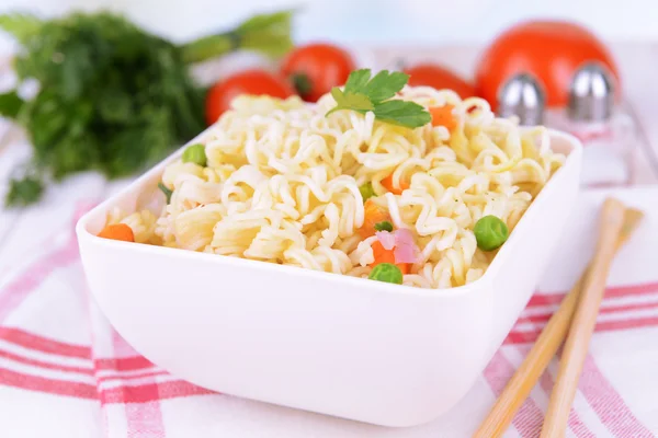 Tasty instant noodles with vegetables in bowl on table close-up — Stock Photo, Image