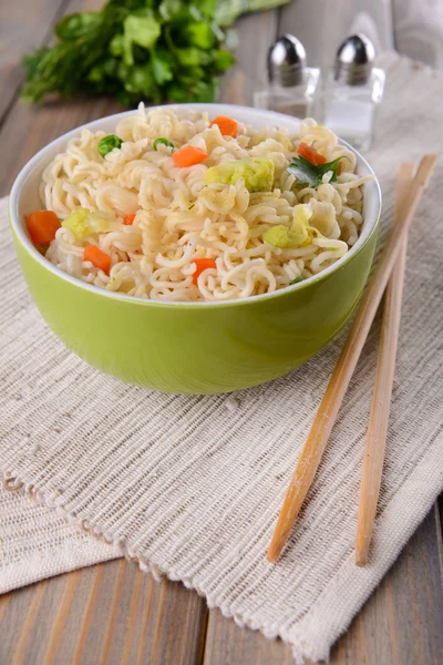 Tasty instant noodles with vegetables in bowl on table close-up — Stock Photo, Image