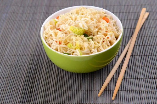 Tasty instant noodles with vegetables in bowl on table close-up — Stock Photo, Image