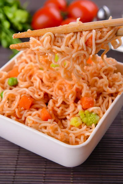 Tasty instant noodles with vegetables in bowl on table close-up — Stock Photo, Image