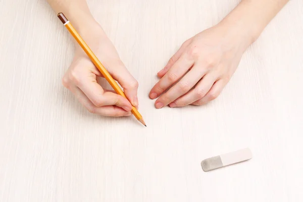 Human hands with pencil and erase rubber on wooden table background — Stock Photo, Image