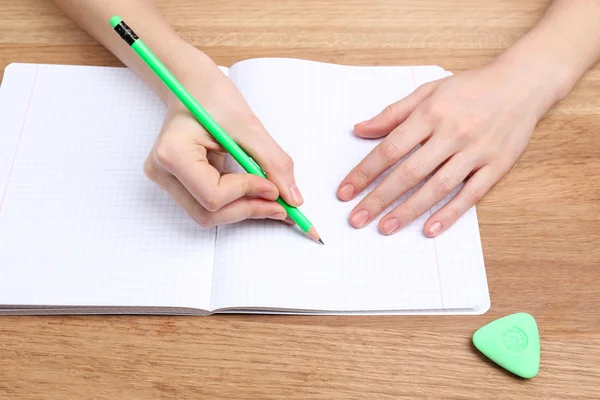 Menschliche Hände mit Bleistiftschrift auf Papier und Gummi auf hölzernem Tischhintergrund löschen — Stockfoto