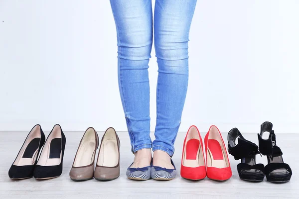 Mädchen wählt Schuhe im Zimmer auf grauem Hintergrund — Stockfoto