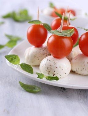 ahşap masa tabakta domates ve fesleğen ile lezzetli mozzarella peyniri
