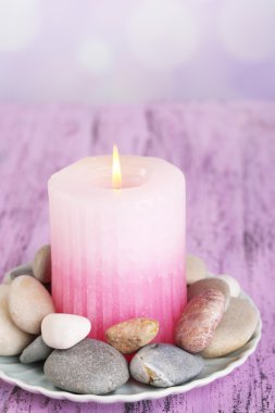 kompozisyon spa taşlar, mum ışık arka plan üzerinde renkli ahşap masa üzerinde