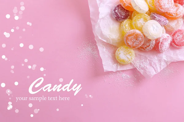 Сладкие разноцветные конфеты на бумаге, на цветном фоне — стоковое фото