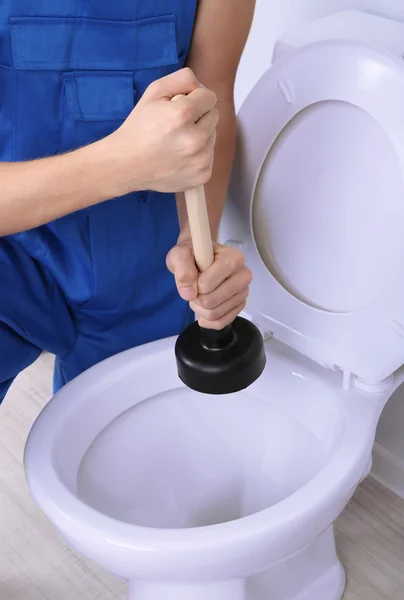 Plumber with toilet plunger on light background — Stock Photo, Image