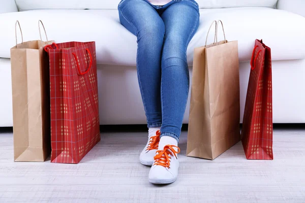 Mulher senta-se no sofá com sacos de compras close-up — Fotografia de Stock