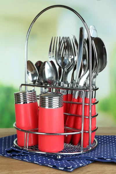 Talheres de cozinha em suporte de metal em mesa de madeira sobre fundo brilhante — Fotografia de Stock