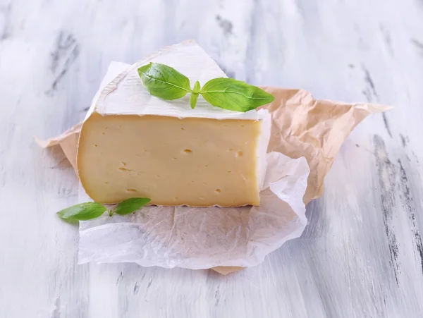 Sabroso queso Camembert con albahaca, sobre mesa de madera —  Fotos de Stock