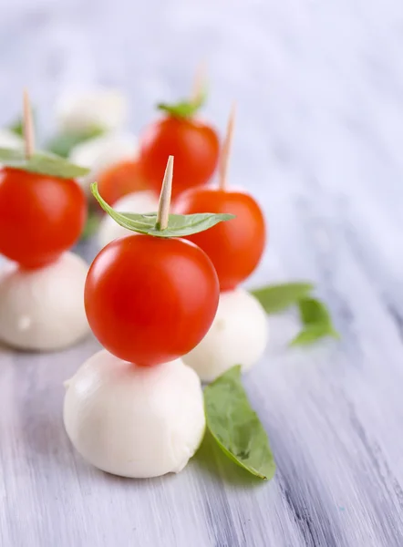 Smakelijke mozzarella kaas met basilicum en tomaten, op houten tafel — Stockfoto