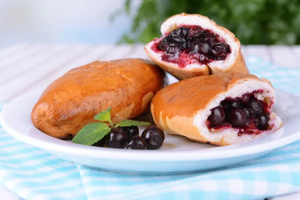 Fresh baked pasties with currant on plate on table close-up — Stock Photo, Image