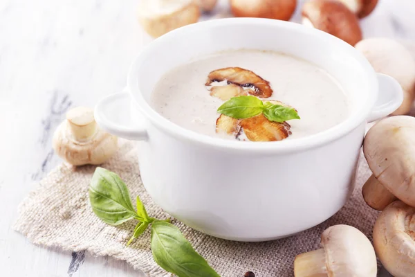 Mushroom soup in white pot, on napkin, on wooden background — Stock Photo, Image