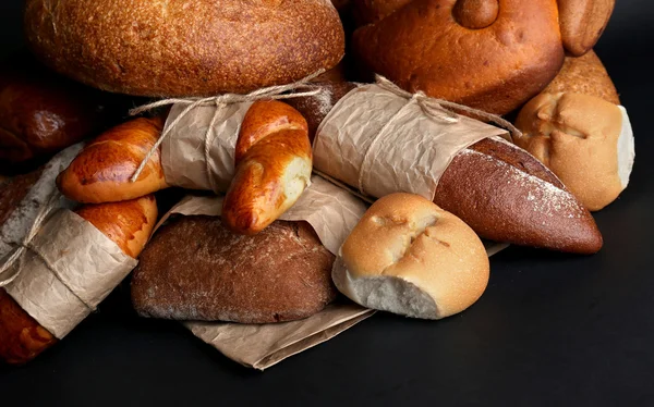 Verschiedene Brotsorten auf schwarzem Hintergrund, Nahaufnahme — Stockfoto
