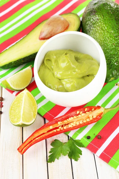 Fresh guacamole in bowl on wooden table — Stock Photo, Image