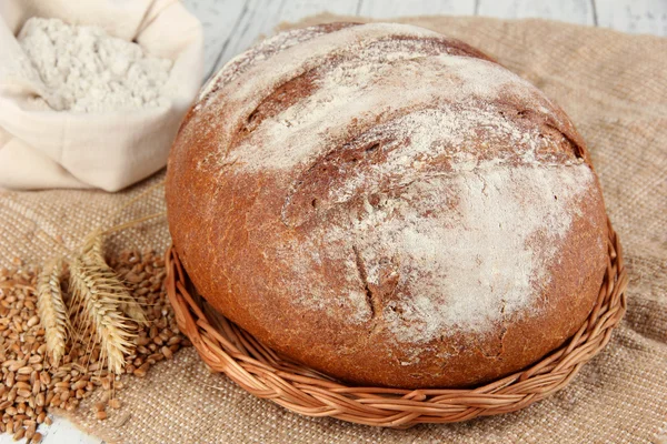 Rye bread with flour and grains on sackcloth on table close up — Stock Photo, Image