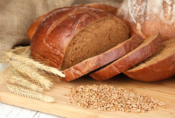 Pan de centeno con granos en la mesa sobre fondo de saco — Foto de Stock