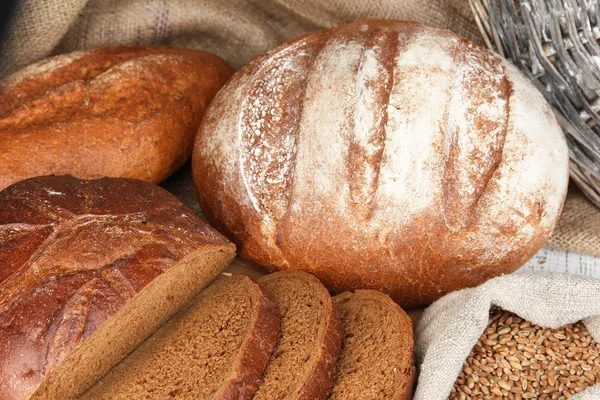 Pane di segale con grani sul tavolo su fondo sacco — Foto Stock