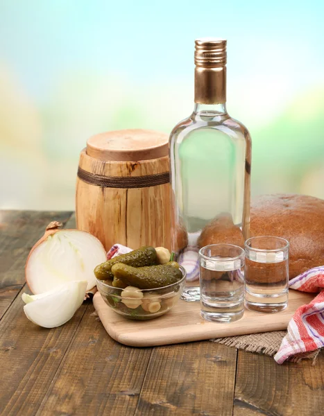 Sammansättning med en flaska vodka och marinerade grönsaker på träbord, på ljus bakgrund — Stockfoto