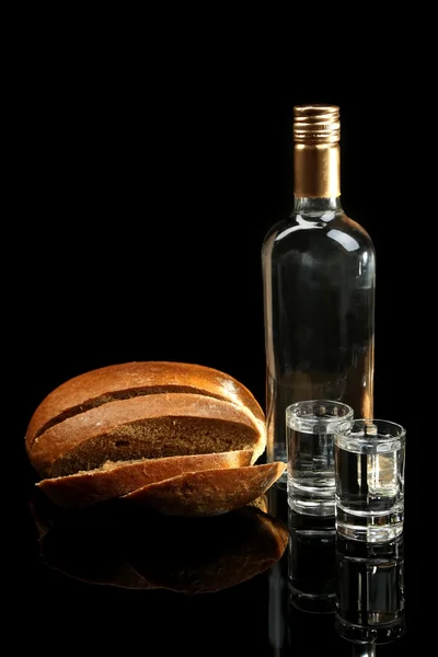 Fles wodka, vers brood en glazen geïsoleerd op zwart — Stockfoto