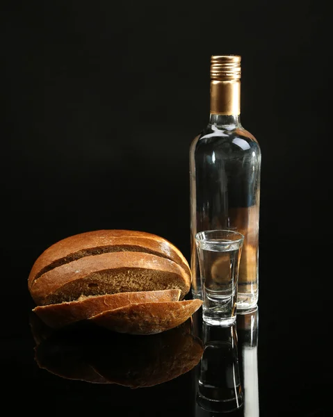 Μπουκάλι βότκα, φρέσκο ψωμί και γυαλιά που απομονώνονται σε μαύρο — Φωτογραφία Αρχείου