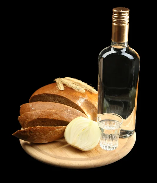 Пляшка горілки, свіжий хліб і склянка на дерев'яній дошці, ізольовані на чорному — стокове фото