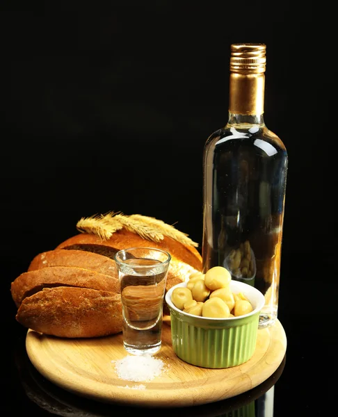 Composição com garrafa de vodka, vidro e vegetais marinados em tábua de madeira, isolados em preto — Fotografia de Stock