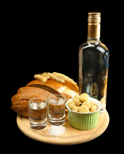 Composition avec bouteille de vodka, verres et légumes marinés sur plateau en bois, isolé sur fond noir — Photo