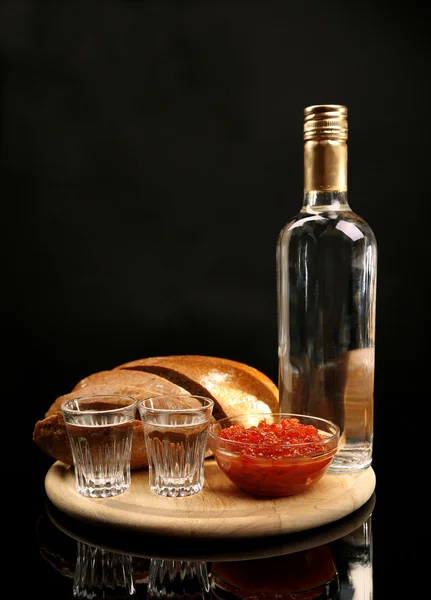 Fles wodka, rode kaviaar, vers brood op houten bord, geïsoleerd op zwart — Stockfoto