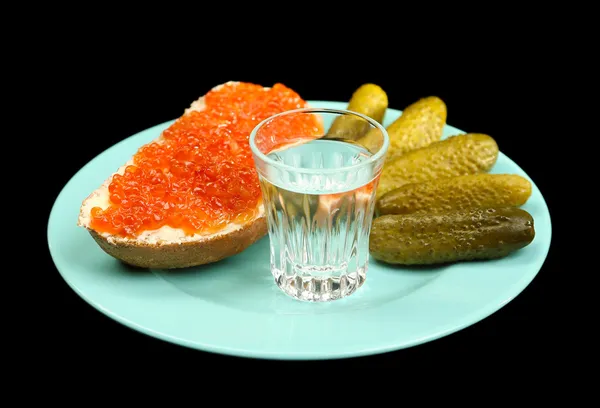 Composición con vaso de vodka y snacks en placa de color, aislado en negro — Foto de Stock