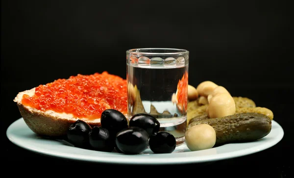 Sammansättning med glas vodka och snacks på färgplåt, isolerade på svart — Stockfoto