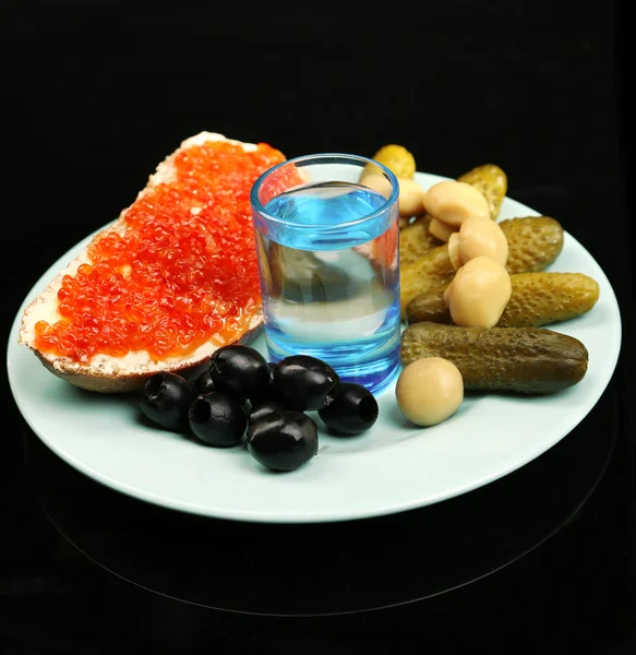 Composition with glass of vodka and snacks on color plate, isolated on black — Stock Photo, Image