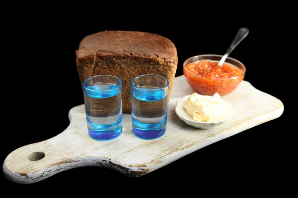 Composición con vasos de vodka, caviar rojo, pan fresco sobre tabla de madera, aislado sobre negro —  Fotos de Stock