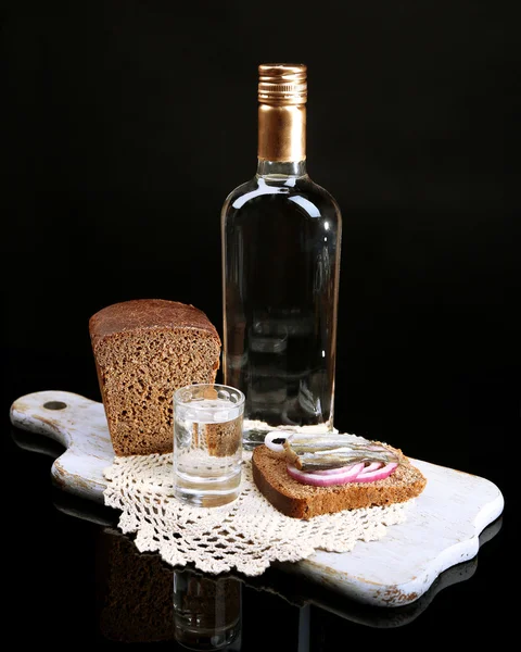 Botella de vodka, sándwich con pescado salado y vasos sobre tabla de madera, aislado sobre negro — Foto de Stock