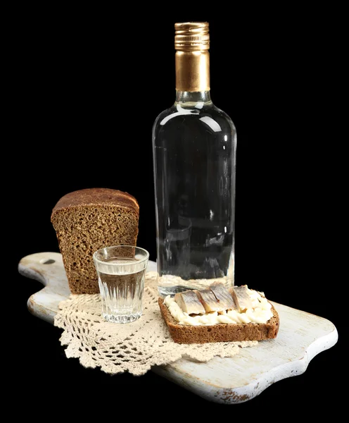 Bouteille de vodka, sandwich au poisson salé et verres sur planche de bois, isolée sur fond noir — Photo