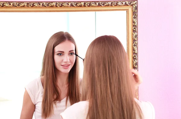 Young beautiful woman making make-up near mirror — Stock Photo, Image