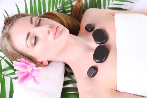 Vacker ung kvinna med sten massage i spasalong — Stockfoto
