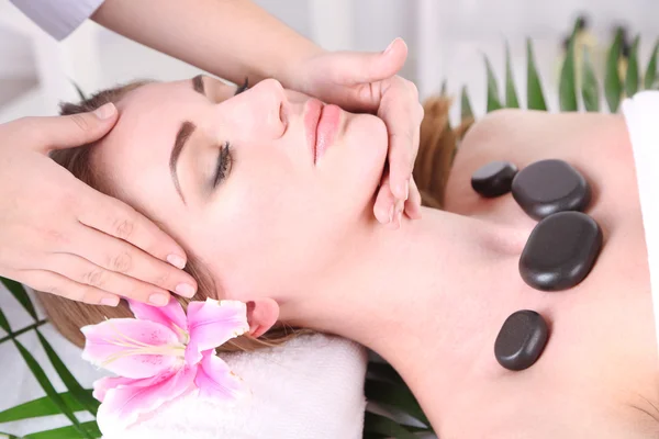 Beautiful young woman having stone massage in spa salon — Stock Photo, Image