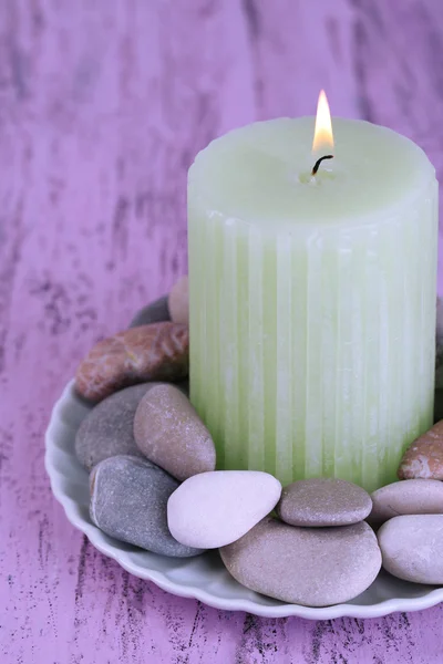 Komposition mit Wellness-Steinen, Kerze auf farbigem Holztisch, auf hellem Hintergrund — Stockfoto