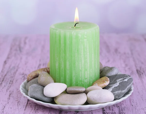 Composizione con pietre termali, candela su tavolo di legno a colori, su sfondo chiaro — Foto Stock